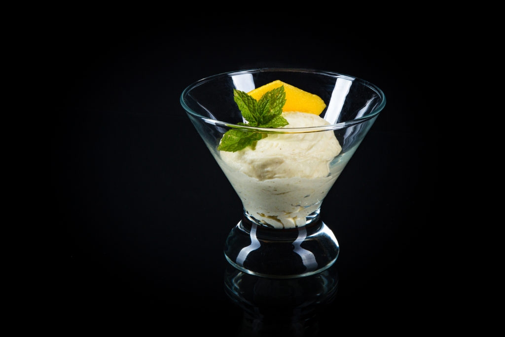 Ein leckeres Dessert ist eine Mangocreme, garniert mit einem frischem grünen Blatt der Zitronenmelisse und einem Mangospalt.